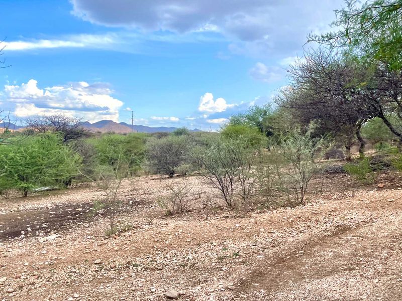 A scenic view of the vacant commercial land featuring natural rocky terrain and native vegetation with distant mountain vistas.
