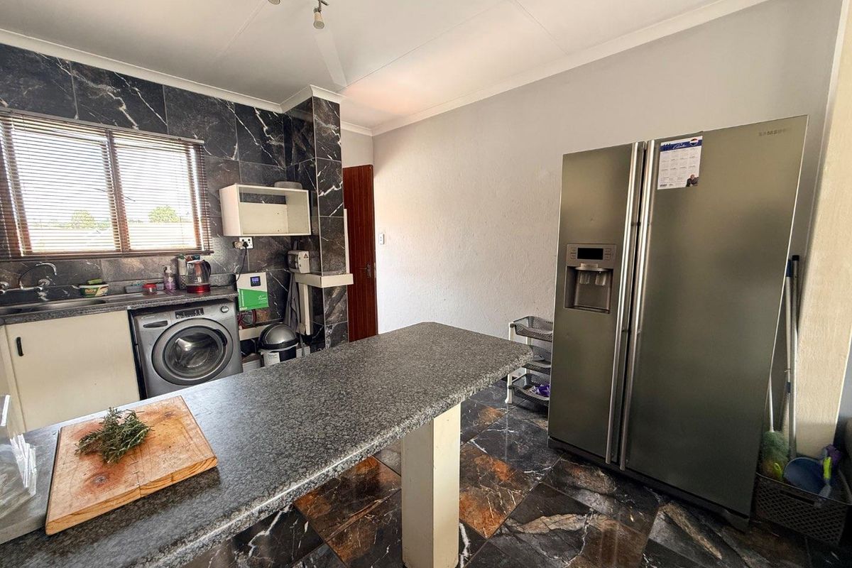 Kitchen featuring dark marble-effect wall and floor tiles, a central breakfast island, and built-in cabinetry with integrated plumbing for laundry appliances.