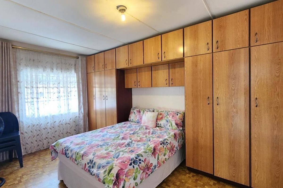 A bedroom featuring extensive wall-to-wall built-in wooden cabinetry and classic parquet flooring, offering ample storage space.
