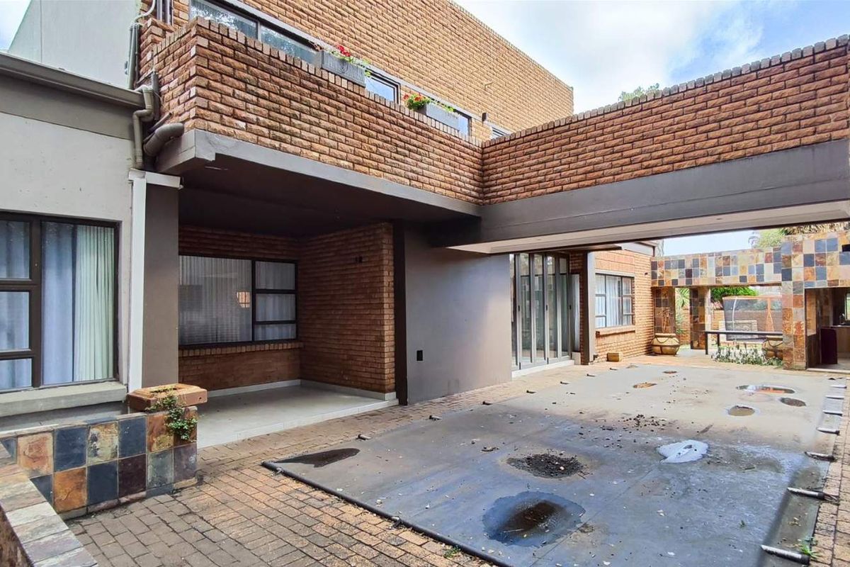 A view of the rear exterior area featuring brick facade, a covered patio space, and paved courtyard area.