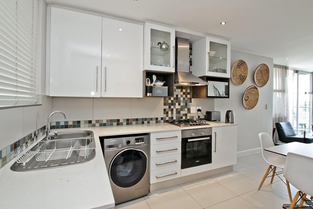 Modern kitchen featuring white cabinetry, mosaic tile backsplash, integrated stainless steel oven, gas hob, extractor fan, and a built-in washing machine.