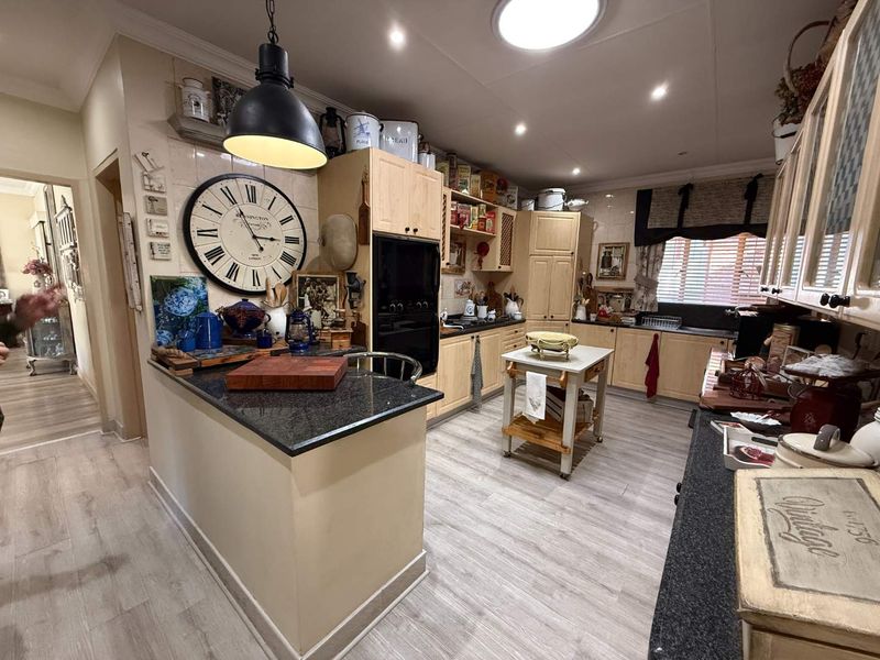 A functional kitchen featuring light wood cabinetry, dark granite countertops, built-in oven, and tiled backsplash with modern laminate flooring.