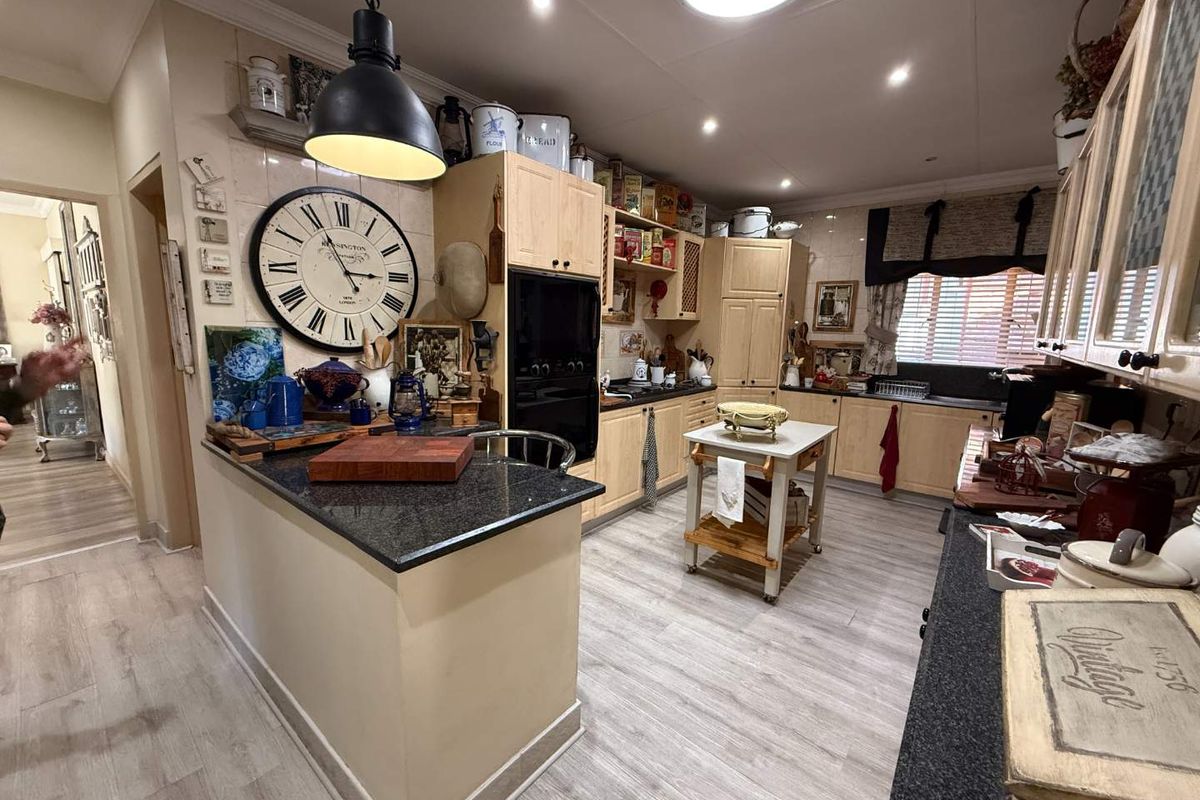 A functional kitchen featuring light wood cabinetry, dark granite countertops, built-in oven, and tiled backsplash with modern laminate flooring.