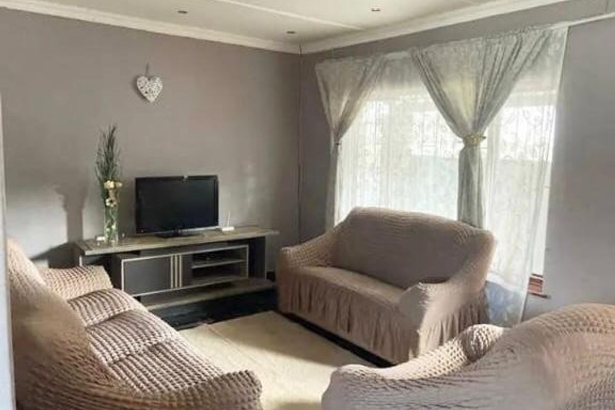 A cozy living room featuring recessed ceiling lighting, coved cornicing, and window security bars, providing a functional and comfortable space.