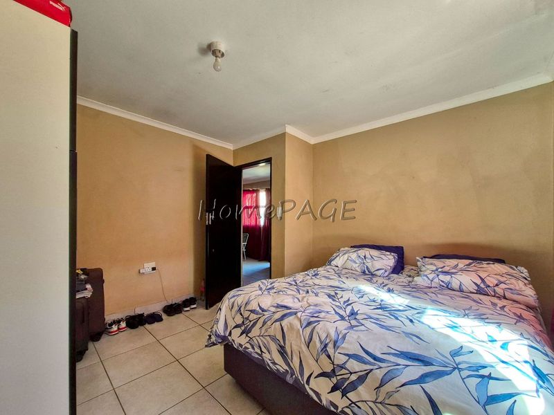 A bedroom featuring tiled flooring and coved ceilings, requiring cosmetic updates to the wall finishes to improve the overall aesthetic.