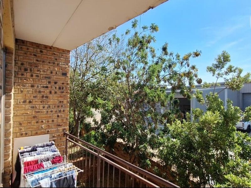 A functional balcony featuring a brick wall and metal railing, offering an outdoor space with views of the surrounding area.