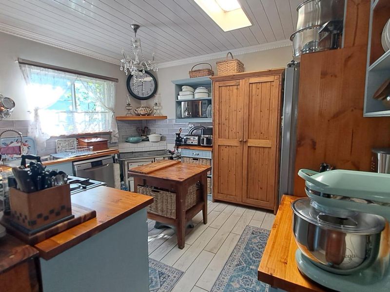 A rustic-style kitchen featuring timber countertops, subway tile backsplash, and a skylight, offering a warm and functional cooking space.