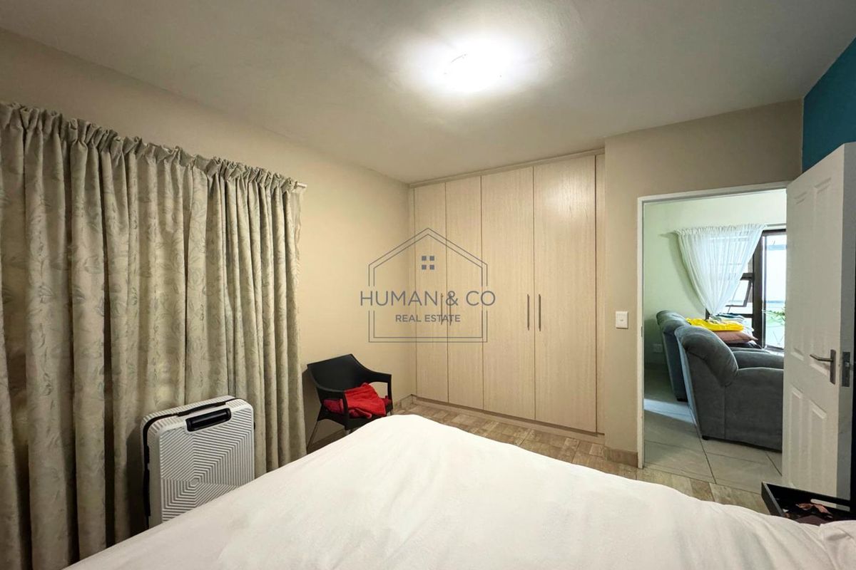 A bedroom featuring built-in cupboards and tiled flooring, with a doorway leading to an adjacent living area.