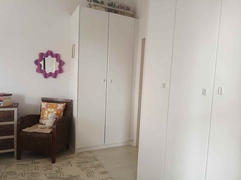 A bedroom featuring white built-in wardrobes and light-toned laminate flooring.