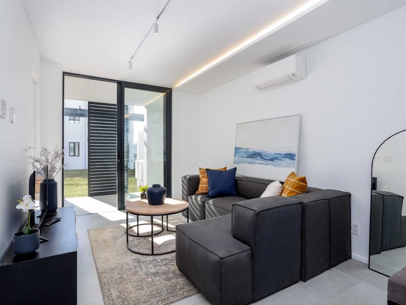 Modern living room featuring tiled flooring, recessed ceiling lighting, a split-system air conditioner, and a large sliding glass door leading to an outdoor area.