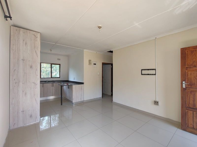 Open plan living area featuring tiled flooring and a compact kitchen with built-in cabinetry and sink.
