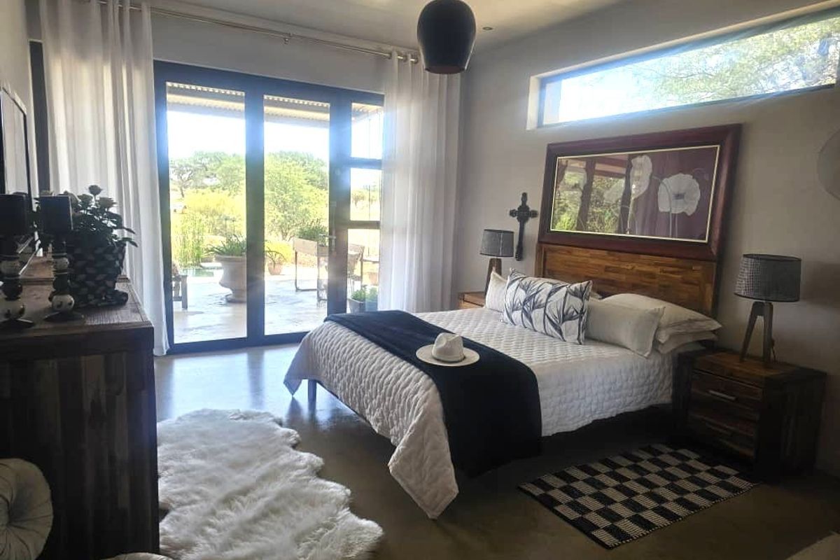 Spacious bedroom featuring polished concrete floors, a high clerestory window, and large sliding glass doors providing direct access to the outdoor patio area.