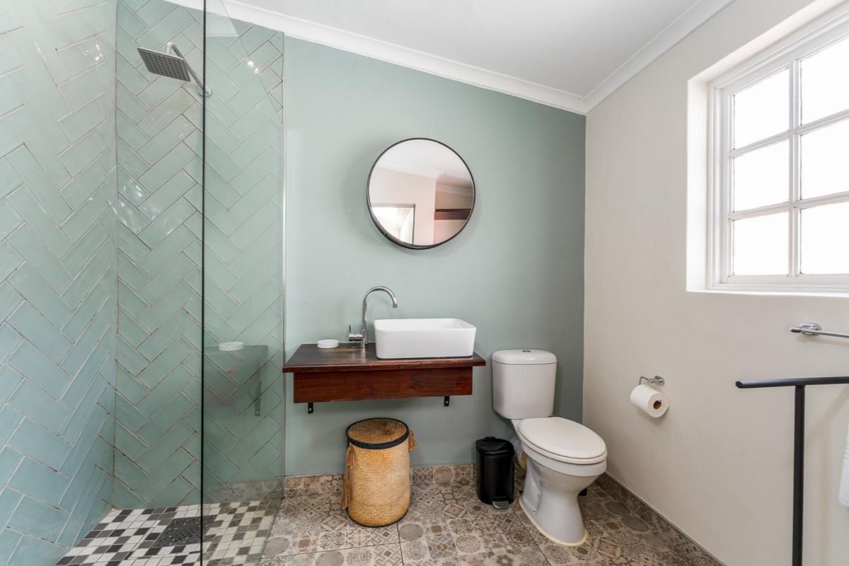 Modern bathroom featuring a glass-enclosed shower with herringbone tiling, a floating timber vanity with a vessel sink, and patterned floor tiles.