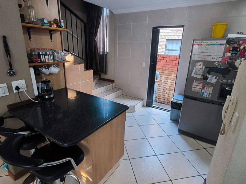 Compact kitchen area featuring a granite breakfast bar, tiled flooring, and direct access to an outdoor space via a rear door.