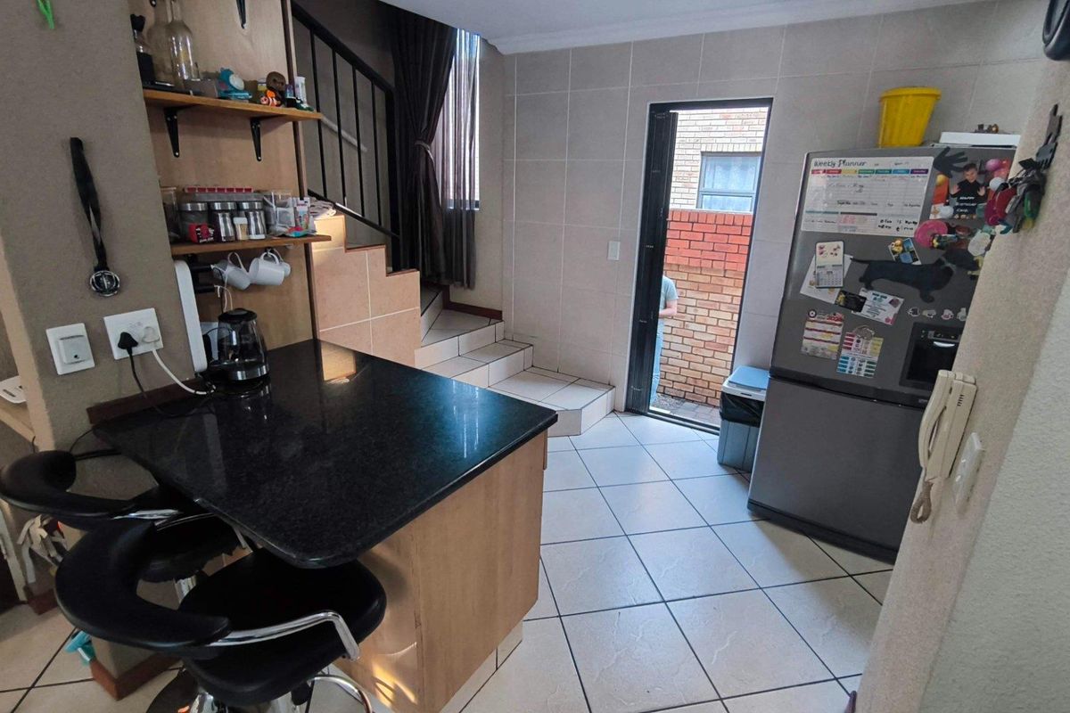 Compact kitchen area featuring a granite breakfast bar, tiled flooring, and direct access to an outdoor space via a rear door.