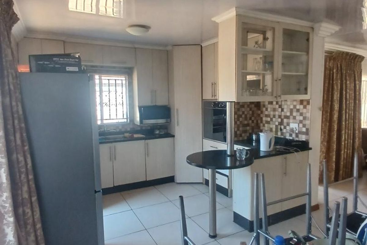 A functional kitchen featuring light-toned cabinetry, a built-in oven, a breakfast bar, and tiled flooring, offering a practical layout for daily meal preparation.