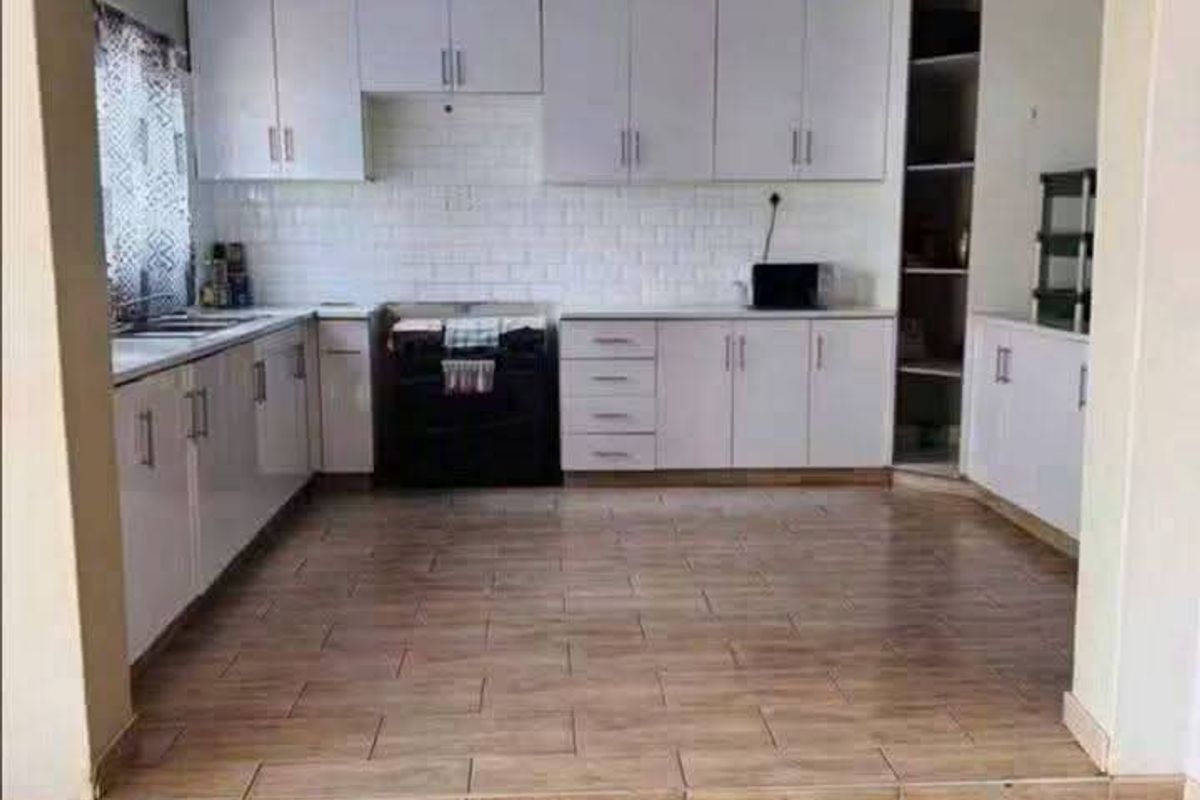 A clean, modern kitchen featuring white cabinetry, subway tile backsplash, built-in oven, and tiled flooring, presented in an open-plan layout.