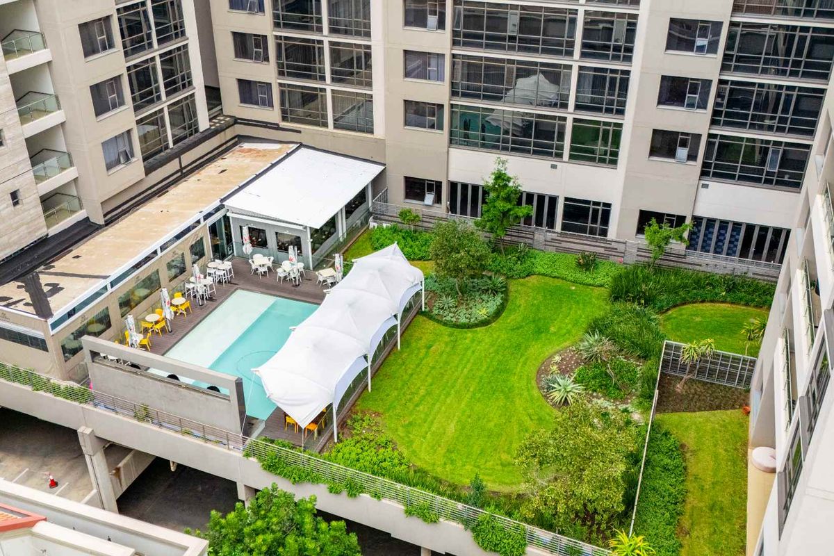 Aerial view of the penthouse complex featuring a landscaped garden, swimming pool, and covered patio area for outdoor recreation.