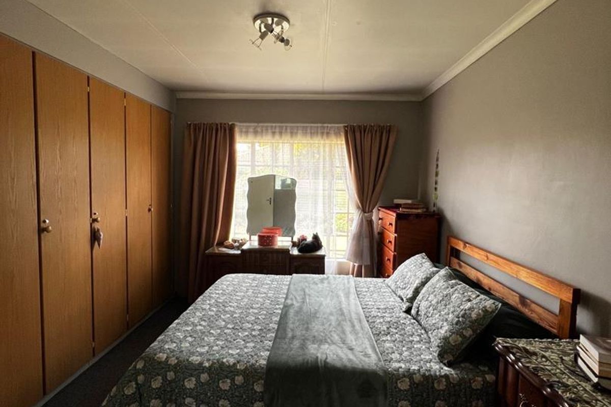 A bedroom featuring built-in wooden cupboards and a window with curtains, providing a functional and traditional living space.
