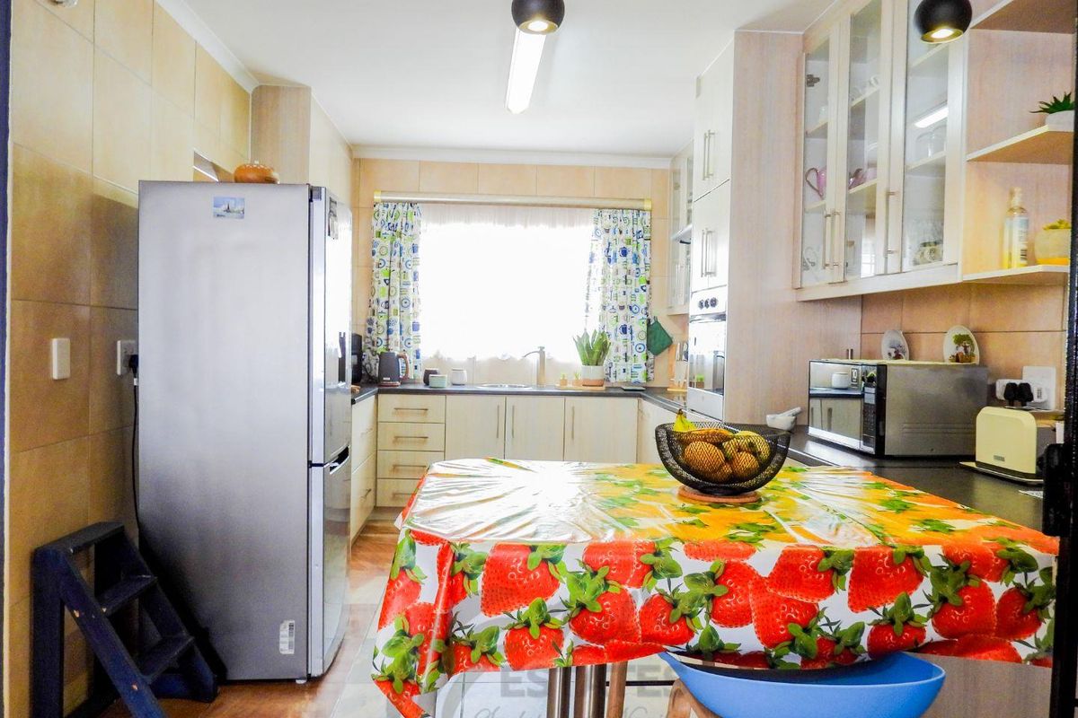 A functional kitchen featuring light-toned cabinetry, tiled splashbacks, integrated oven, and a window providing natural light over the sink area.