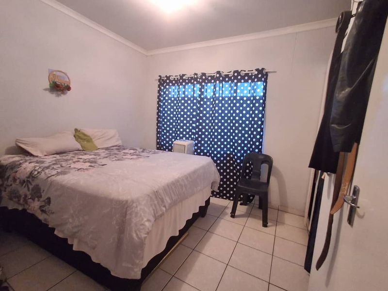 A standard bedroom featuring tiled flooring and a built-in cupboard, providing a functional living space.