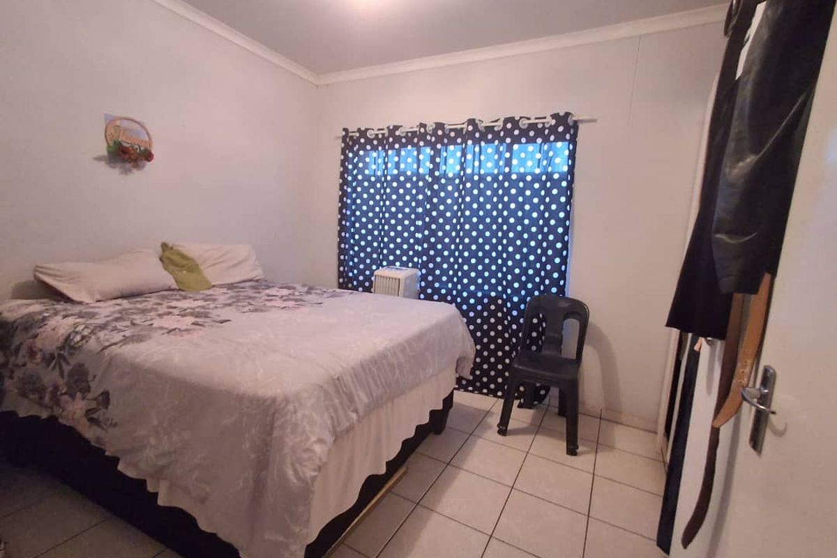 A standard bedroom featuring tiled flooring and a built-in cupboard, providing a functional living space.