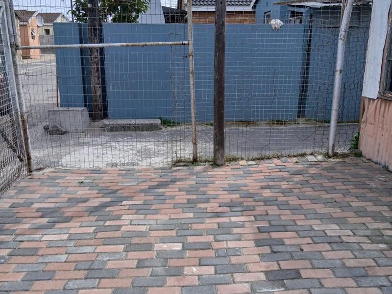 A paved rear courtyard area enclosed by wire mesh fencing and a concrete boundary wall.
