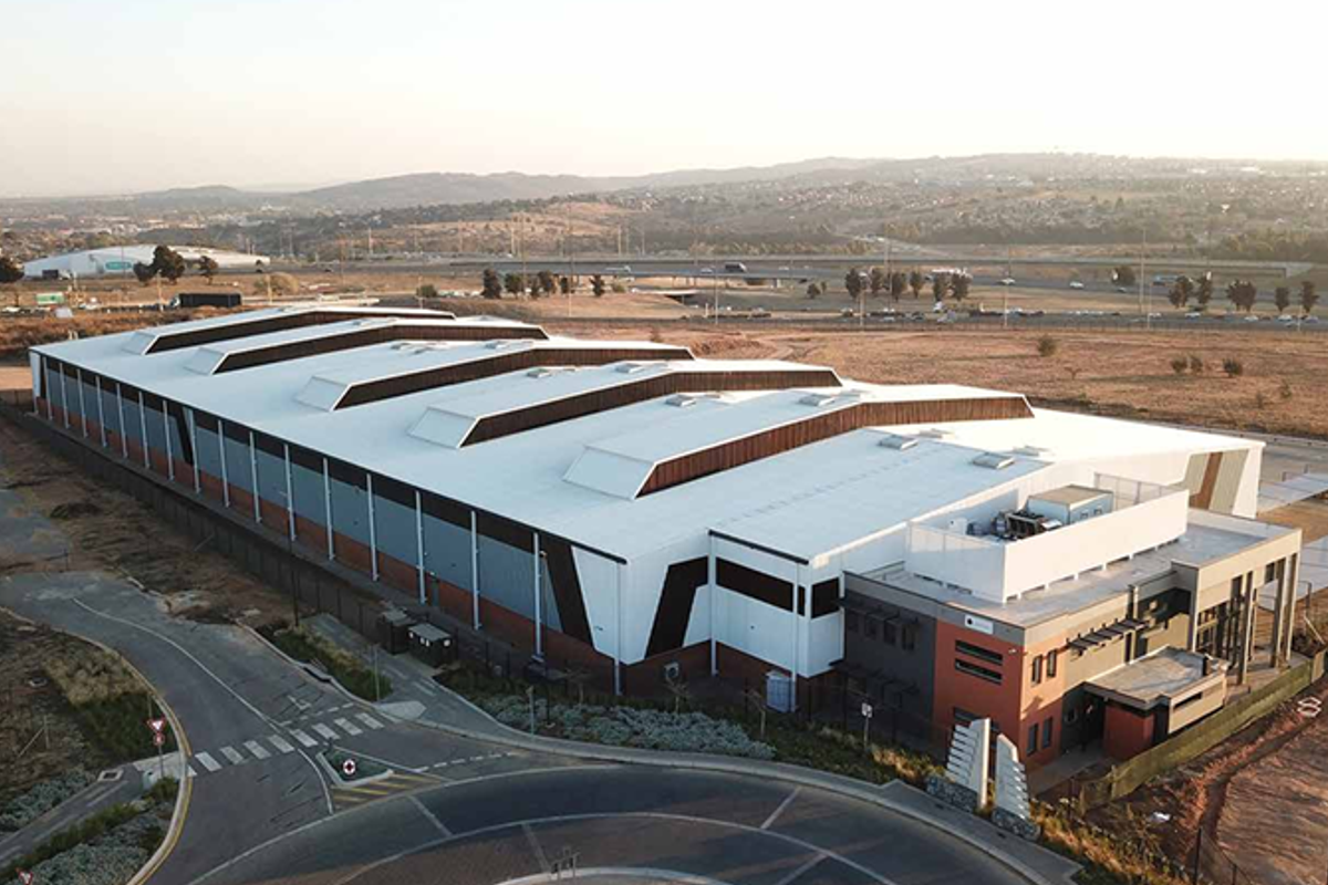 Aerial view of a modern industrial warehouse facility featuring a large span roof with skylights and an integrated office block.