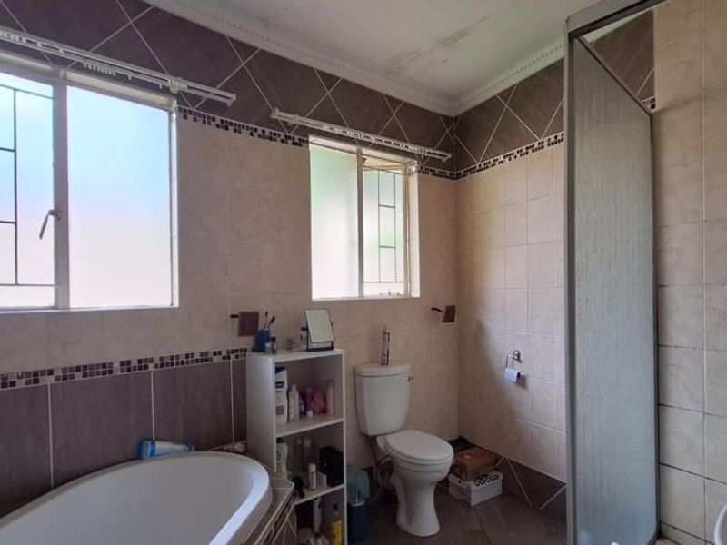 A functional bathroom featuring a bathtub, separate shower enclosure, toilet, and tiled finishes, requiring minor cosmetic attention to the ceiling.