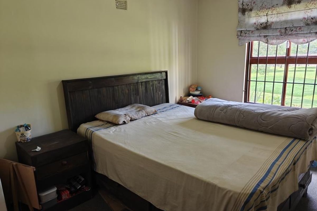 A bedroom featuring a window with security bars and a wall-mounted ventilation vent, providing a functional space with basic finishes.