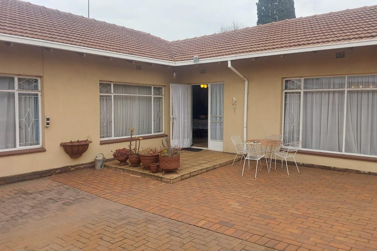 A rear courtyard featuring brick paving, tiled roof, and large windows, providing direct access to the home's interior living space.