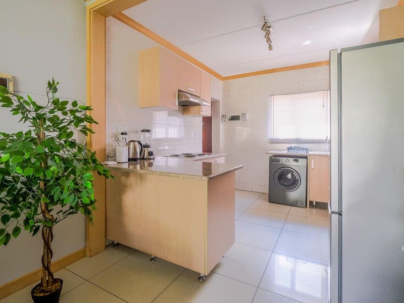 Functional kitchen featuring granite countertops, built-in cabinetry, a breakfast nook, and tiled flooring with a dedicated space for laundry appliances.
