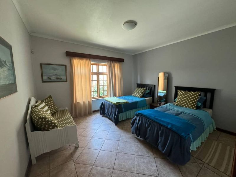 A bedroom featuring tiled flooring, a wooden window frame, and neutral wall finishes.