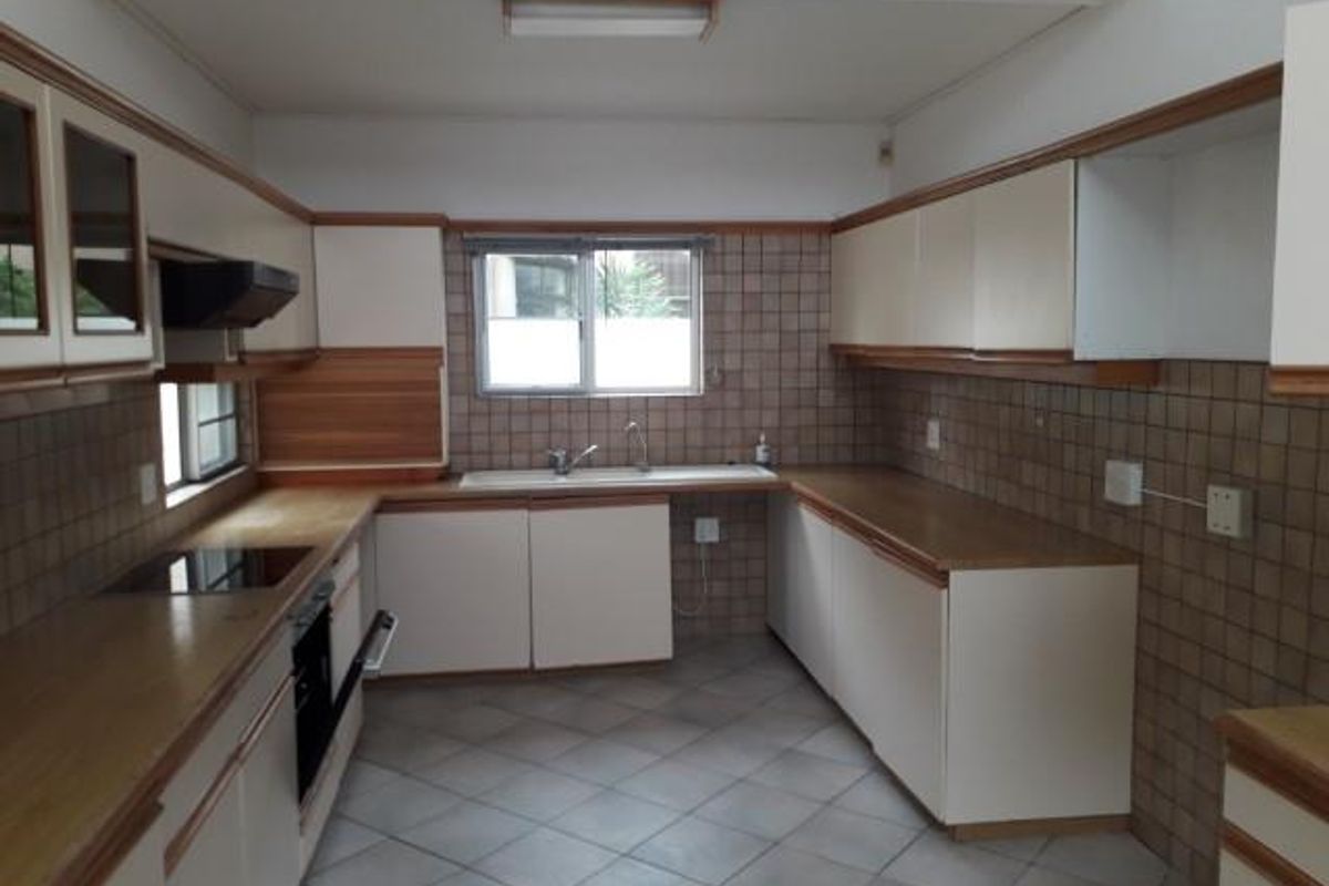 A functional kitchen featuring built-in cabinetry, a tiled backsplash, integrated oven and hob, and tiled flooring.
