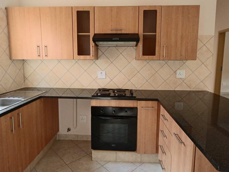 A functional kitchen featuring laminate cabinetry, granite countertops, a built-in oven with gas hob, extractor fan, and tiled backsplash.