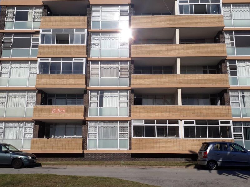 Front elevation of a multi-story apartment building featuring brick cladding, multiple balconies, and large aluminium-framed windows.