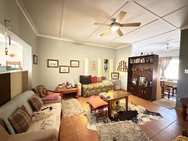 Spacious living area featuring tiled flooring, a ceiling fan, and unique vertical slit windows, offering a comfortable and functional layout.