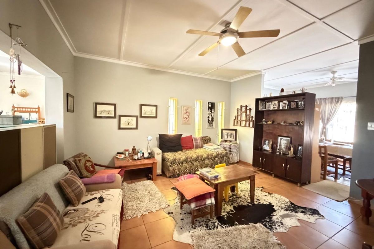 Spacious living area featuring tiled flooring, a ceiling fan, and unique vertical slit windows, offering a comfortable and functional layout.