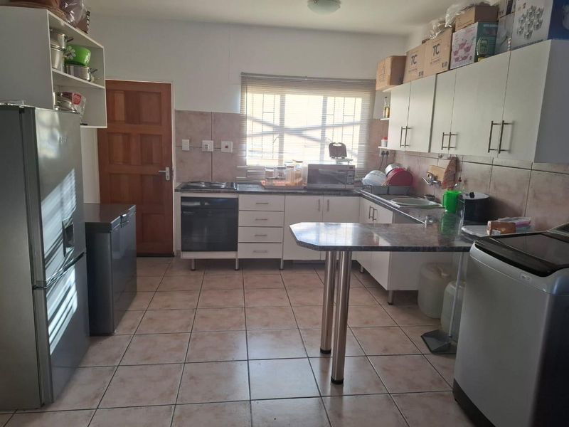 Functional kitchen featuring built-in cabinetry, laminate countertops, integrated oven and hob, tiled flooring, and a breakfast bar area.
