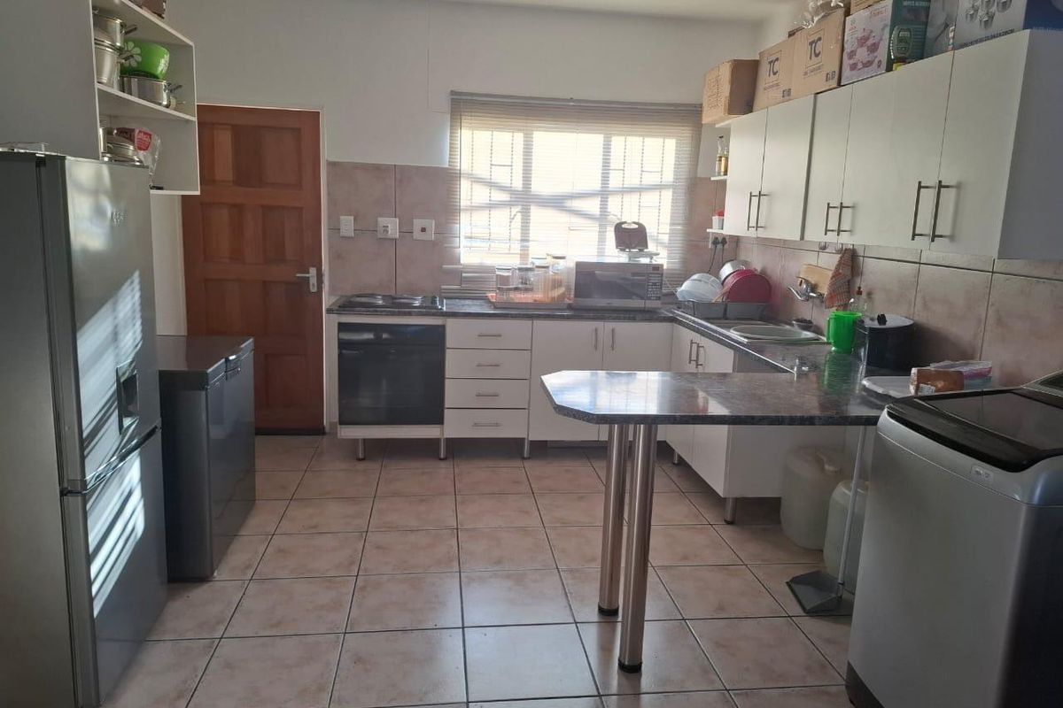 Functional kitchen featuring built-in cabinetry, laminate countertops, integrated oven and hob, tiled flooring, and a breakfast bar area.