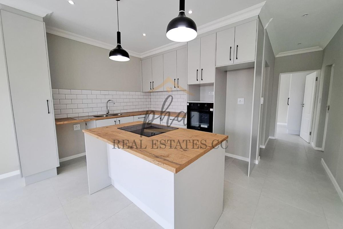 Modern kitchen featuring light grey cabinetry, wood-look countertops, a central island with a built-in cooktop, and a classic subway tile backsplash.