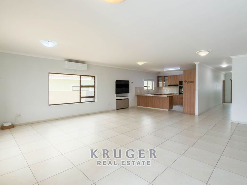 Spacious open-plan living area featuring tiled floors, a modern kitchen with built-in cabinetry, and an integrated air conditioning unit.