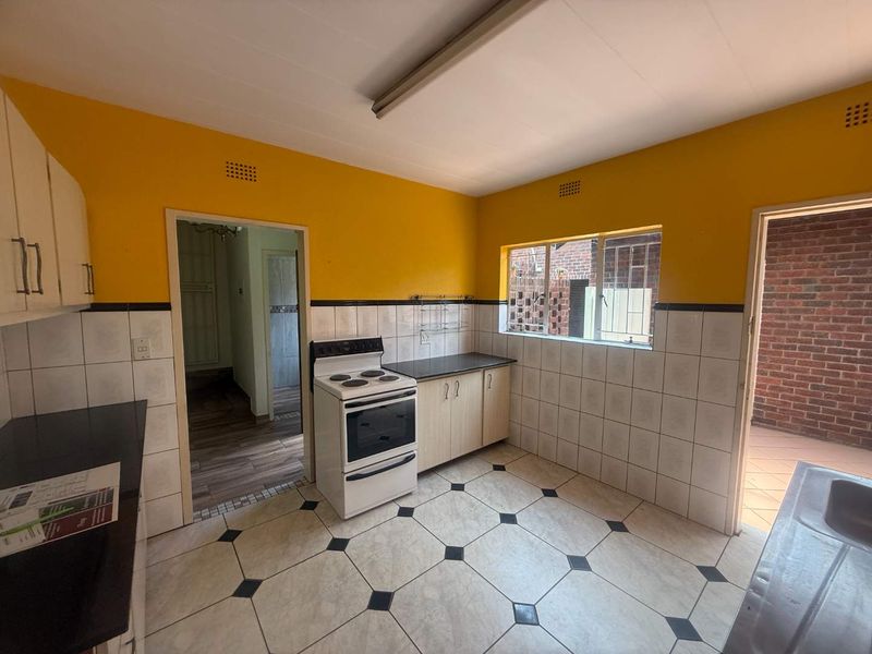 A functional kitchen featuring tiled flooring, built-in cabinetry, and a freestanding stove, offering a blank canvas for potential modern updates.