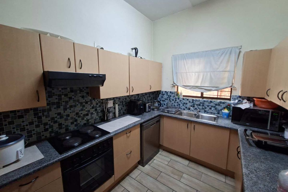 Functional kitchen featuring laminate cabinetry, granite-look countertops, a built-in electric oven with extractor fan, and a double-basin sink.