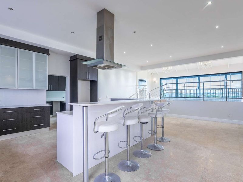 Spacious open-plan kitchen and living area featuring modern cabinetry, a central island with breakfast bar, and seamless access to an elevated balcony.