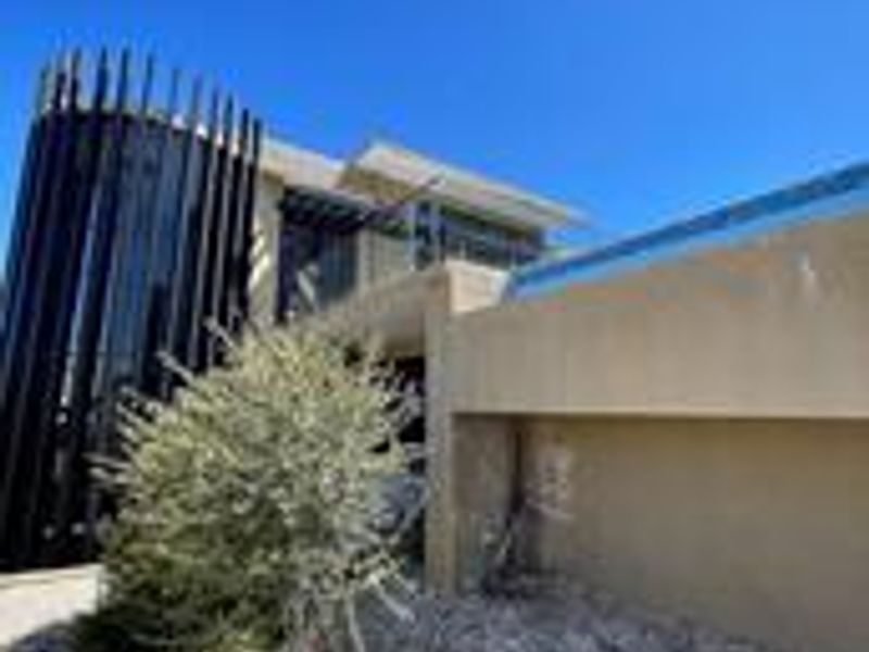 Modern architectural front facade featuring a distinctive vertical slat design and an upper-level balcony.