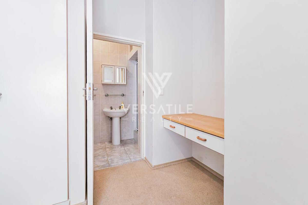 A functional bathroom area featuring a pedestal basin and an adjacent built-in vanity desk with storage drawers.