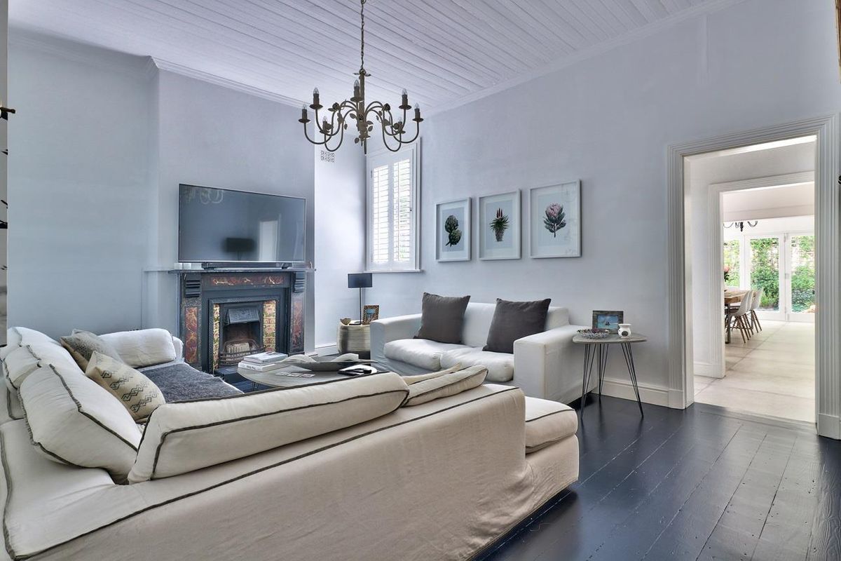 Elegant living room featuring dark timber flooring, a classic fireplace, and a characterful timber panelled ceiling with plantation shutters.