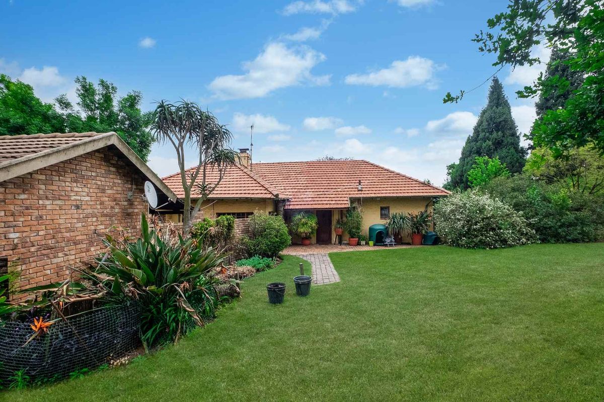 A view of the rear exterior of the farm property, featuring a brick facade, tiled roof, and a well-maintained lawn with a paved walkway.