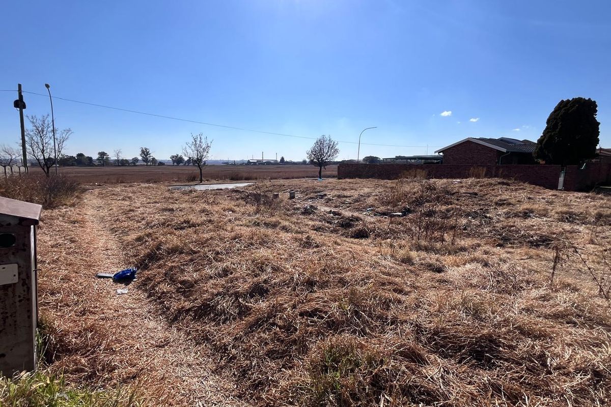 A vacant residential plot featuring dry, overgrown grass and open land, offering a blank canvas for future development.